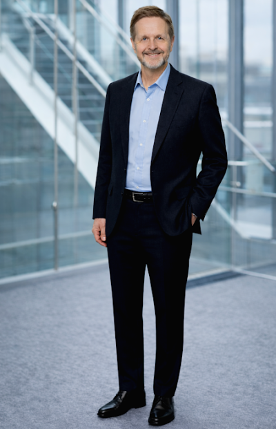 Herr Kurz steht an einem Stehtisch, auf dem ein Tablet steht.